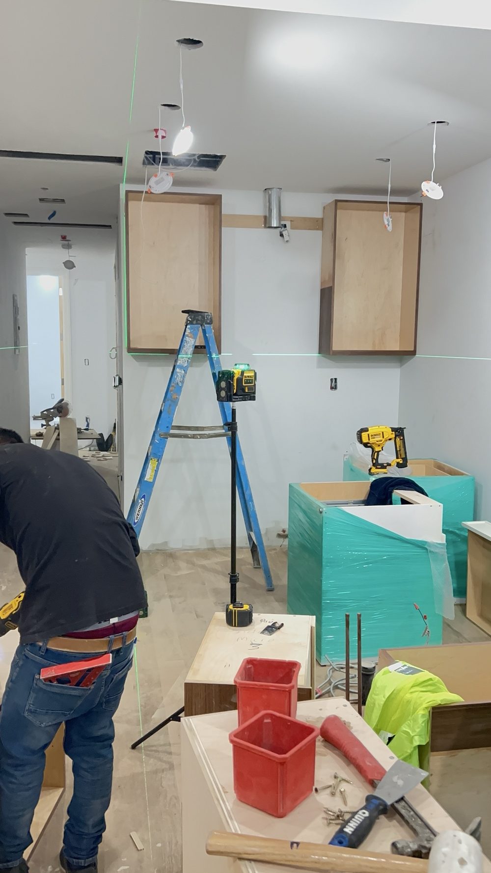 Cabinet installation in progress with a laser level and ladder