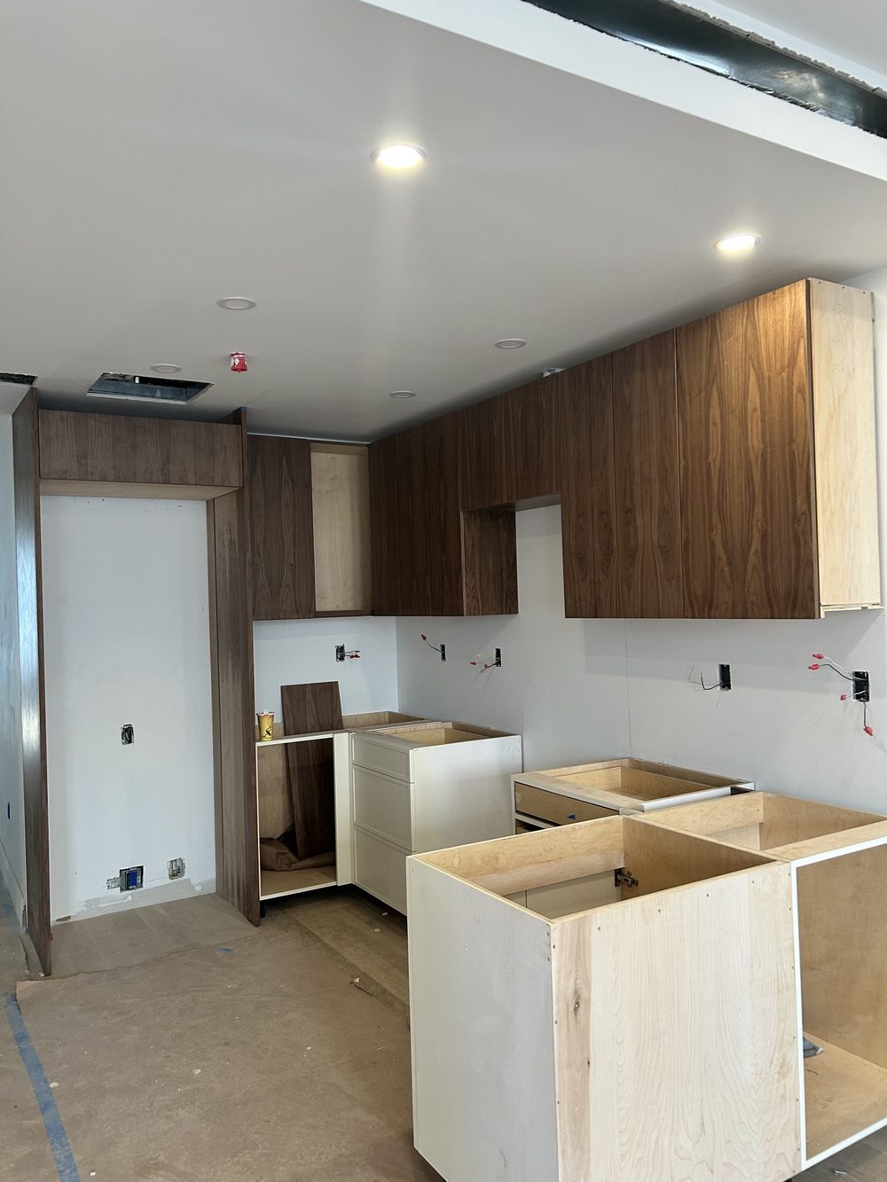 Kitchen under construction with walnut wall cabinets and a new custom island being built