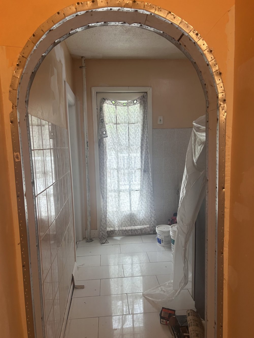 Arched doorway under construction with new ceramic tile walls and floor